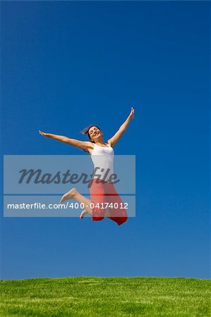 Beautiful young woman jumping on  a green meadow