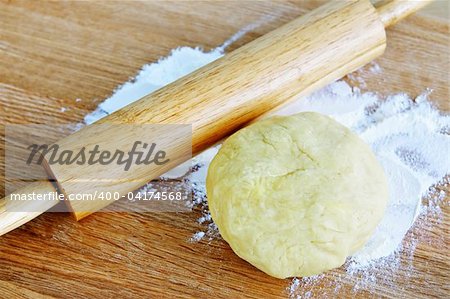 Wooden rolling pin and ball of cookie dough with flour