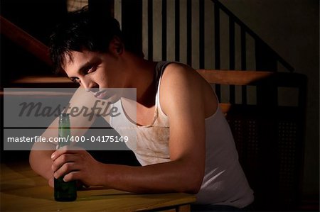 Depressed young man with bottle of beer