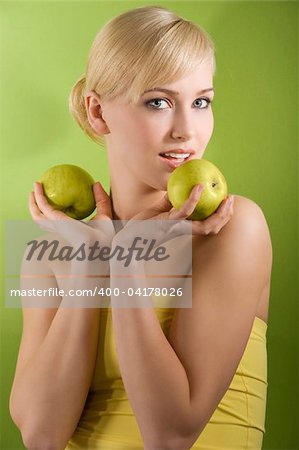 very cute blond girl with yellow top and green apple looking in camera