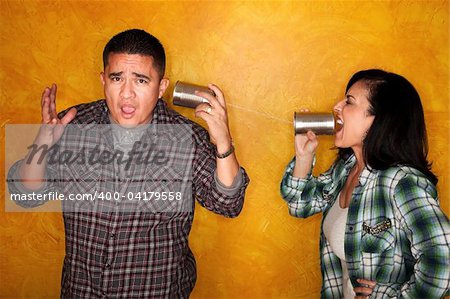 Attractive Hispanic man and woman communicate through tin cans