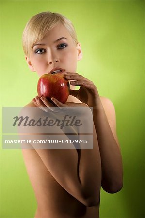 fashion and glamour shot of a nude young woman with apple on green background