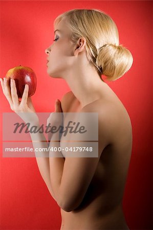 fashion shot of a glamour sensual girl looking a red apple against colored background