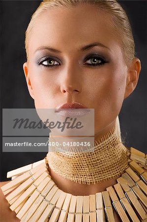 closeup portrait of attractive blond woman like an amazon with a necklace made of wood peg