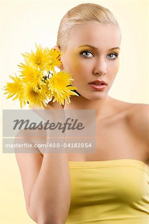 young and beauty blond girl wearing a yellow top keeping yellow flower. wellness concept