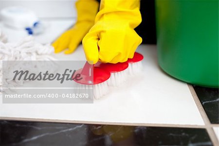Woman cleaning a bathroom's floor with a yellow rubber glove