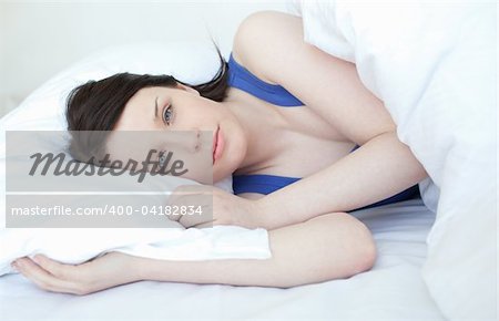Delighted woman relaxing on a bed at home