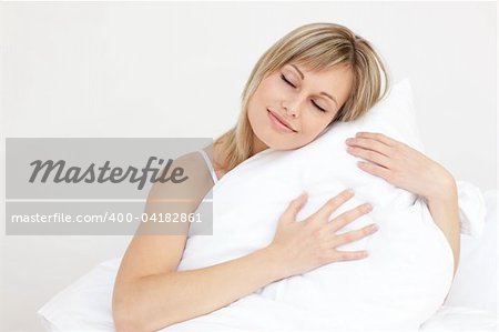 Relaxed woman hugging her cushion sitting on her bed in the morning