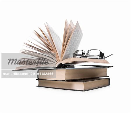 pile of books with one book open and eyeglasses  on white background