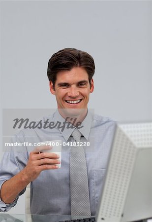 Happy caucasian businessman holding a drinking cup sitting at his desk