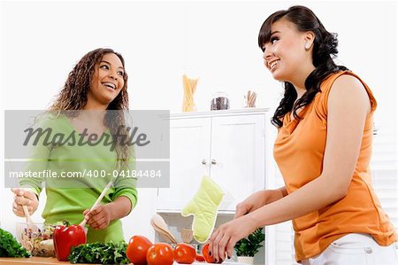 Stock image of two young women in kitchen preparing a salad