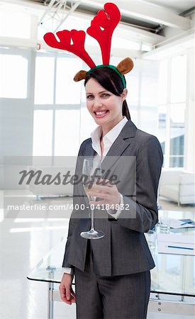 Smiling businesswoman with a novelty Christmas hat toasting with Champagne in the office