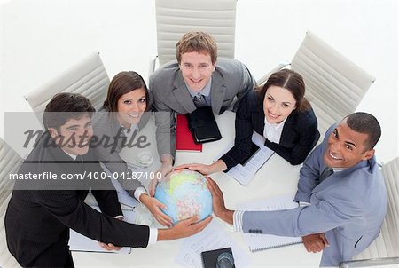 High angle of a diverse business team holding a terrestrial globe in the office