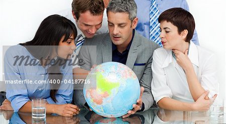 International business people looking at a terrestrial globe in the office