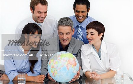 Smiling business people looking at a terrestrial globe in the office