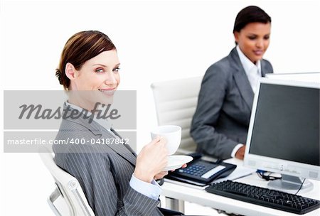 Smiling female business partners having a break drinking coffee in the office