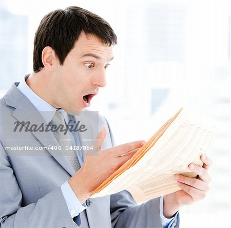 Portrait of a exited businessman reading a newspaper in the office