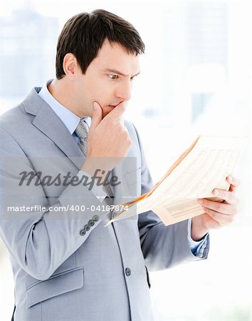 Portrait of a thinking businessman reading a newspaper in the office