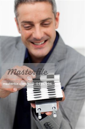 Charming businessman consulting a business card holder in the office