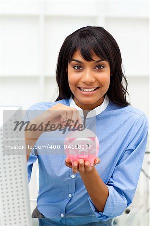 Smiling businesswoman saving money in a piggybank in the office