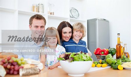 Smiling parents and their children preparing dinner together in the kitchen