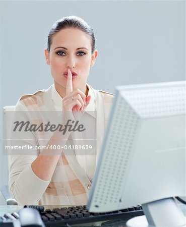 Attractive businesswoman at a computer asking for silence in the office