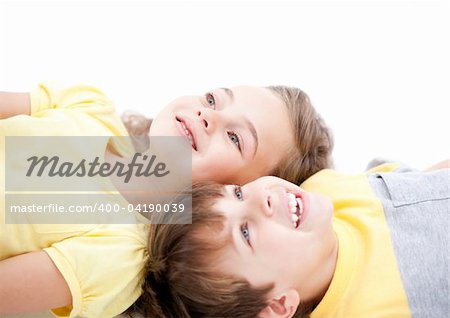 Smiling childrens lying on the floor together at home