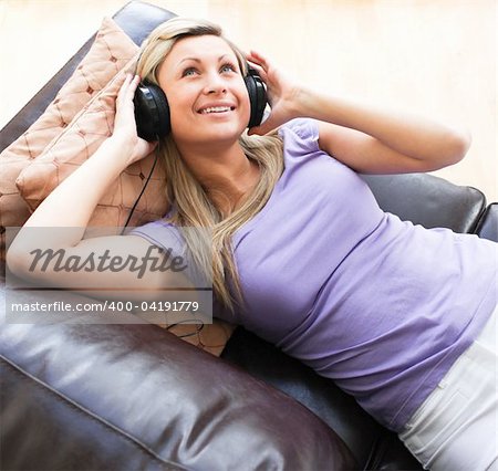 Happy woman using headphones on a sofa