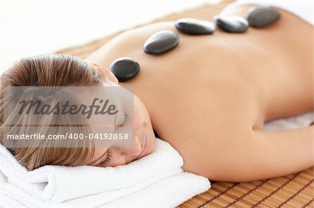 Bright woman having a stone therapy against a white background