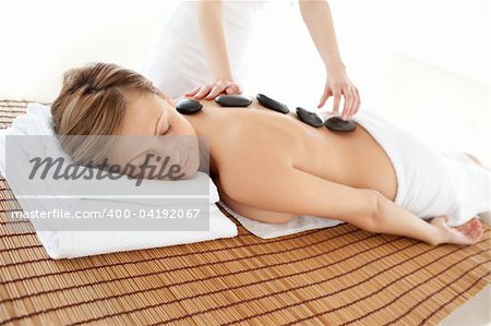 Delighted woman lying on a massage table having a stone therapy