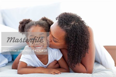 Loving woman  kissing her daughter lying down on bed at home