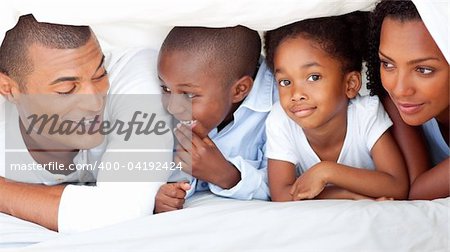 Cheerful family having fun lying down on bed at home