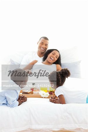 Cheerful family having breakfast in the bedroom at home