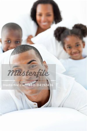 Attractive man having fun with his family lying down on bed