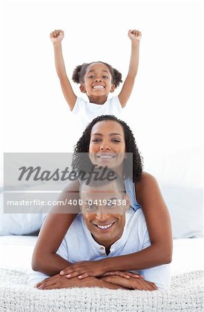 Adorable little girl having fun with her parents in the bedroom