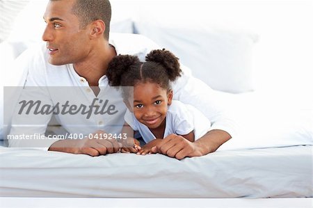 Father and his daughter having fun lying on a bed