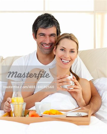 Close-up of couple having breakfast lying in the bed at home