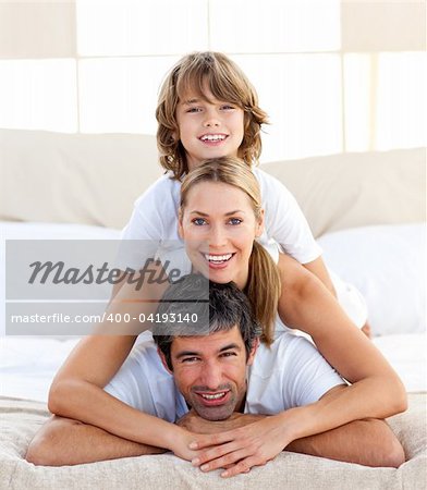 Little boy and his parents playing lying on the bed