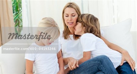 Blond mother having fun with her children sitting on sofa