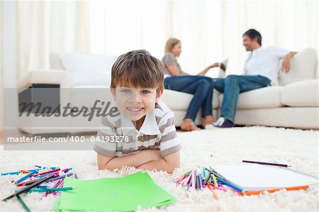 Smiling child drawing lying on the floor in the living room
