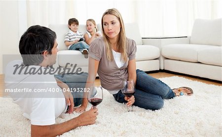 Romantic couple talking with glasses of wine lying on the floor