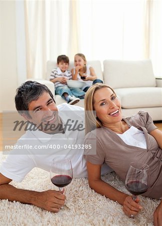 Smiling lovers drinking wine lying on the floor in the living room