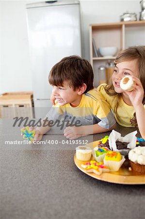 Smiling children showing their cookies in the kitchen