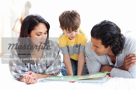 Affectionate family reading book together lying on the floor
