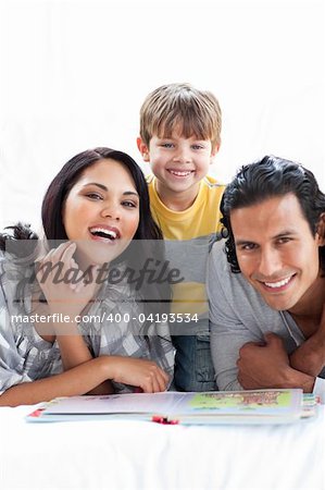Jolly family reading book together lying on the floor