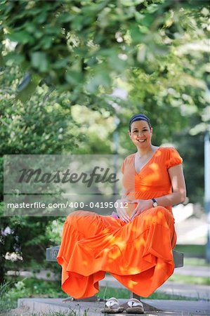 beautiful young happy pregnant woman outdoor in bright nature in orange dress