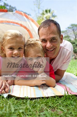 Happy father and his children lying on the grass in a park