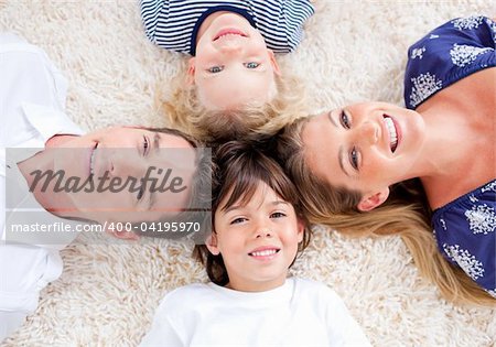Smiling young family lying on the floor with heads together