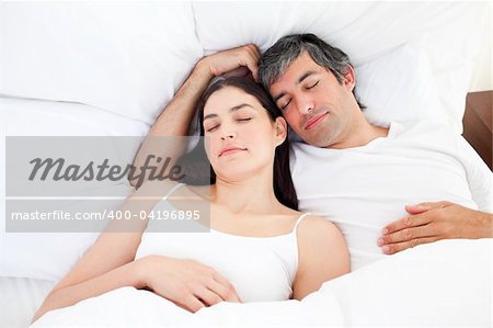 Affectionate couple hugging lying in their bed at home