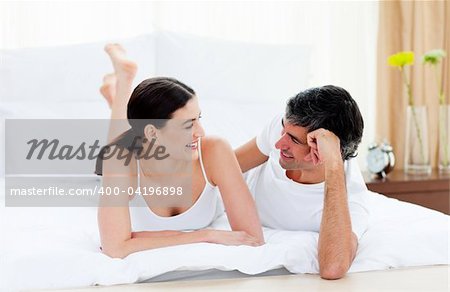 Happy affectionate couple interacting lying on their bed